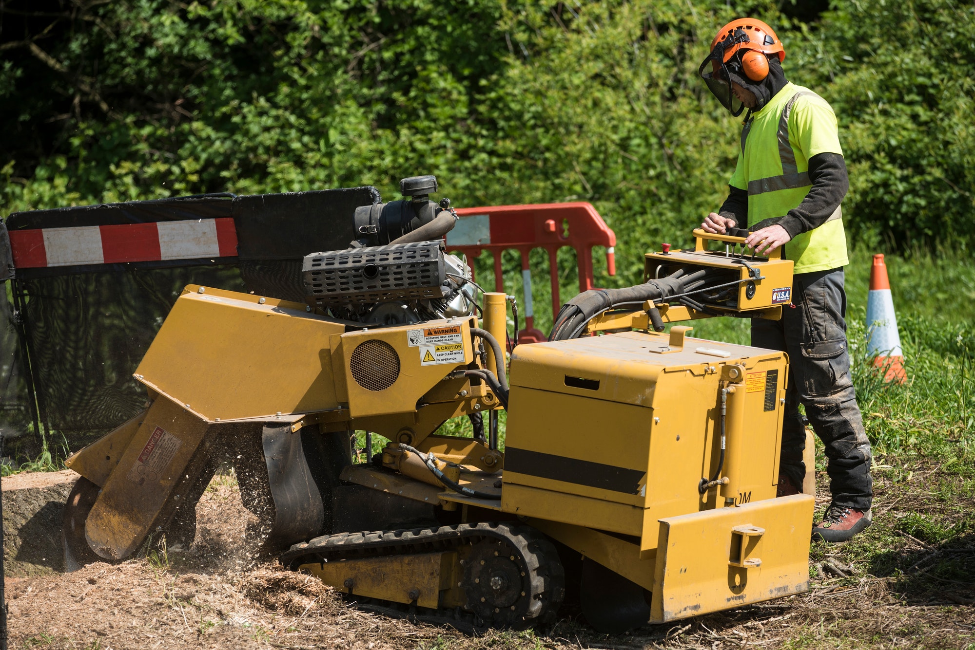 A heavy duty stump grinder with rubber caterpillar tracks being used to grind out the remaining tree